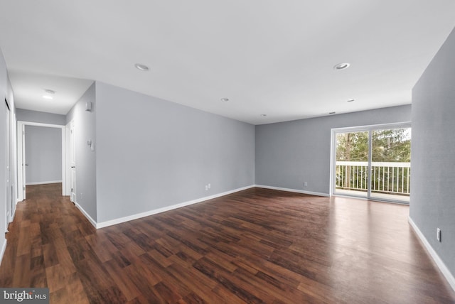 empty room featuring baseboards, dark wood-type flooring, and recessed lighting