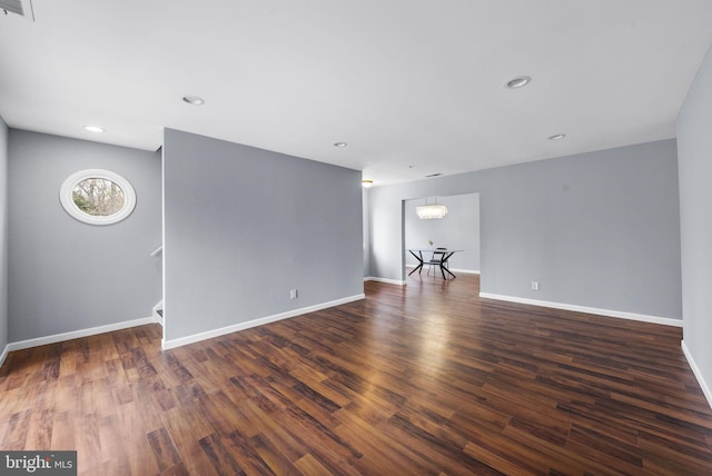 unfurnished living room featuring baseboards, a notable chandelier, dark wood-type flooring, visible vents, and recessed lighting