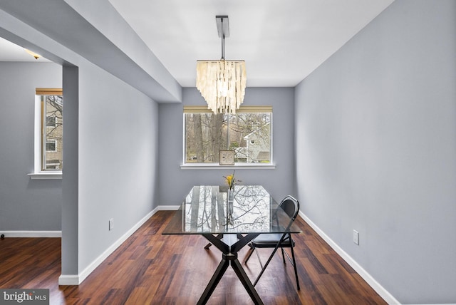 dining room featuring baseboards, wood finished floors, and an inviting chandelier