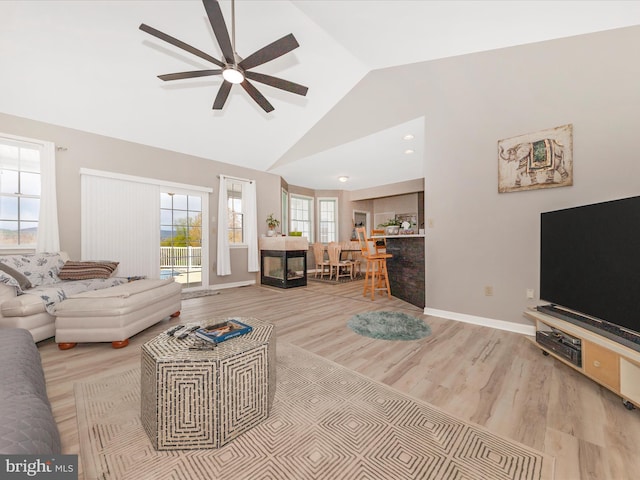 living room with high vaulted ceiling, light wood-style flooring, a ceiling fan, and baseboards