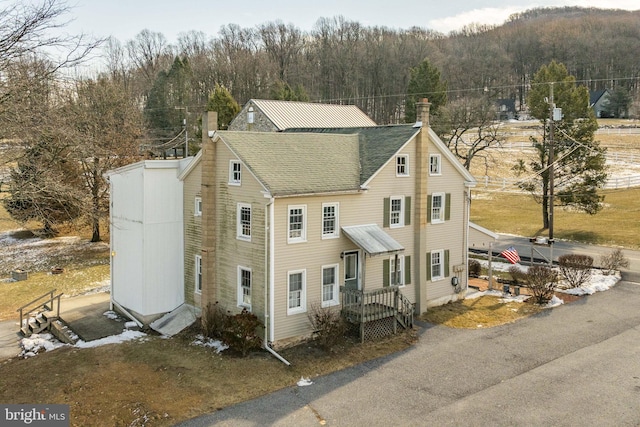 view of front of property featuring a chimney and a shingled roof