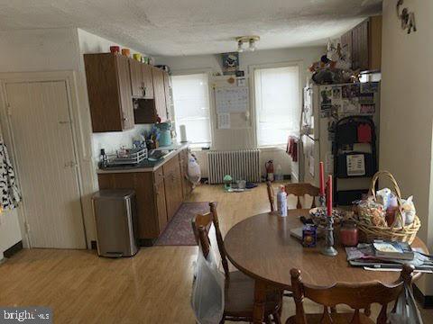 kitchen with radiator heating unit, light wood-style floors, and brown cabinetry