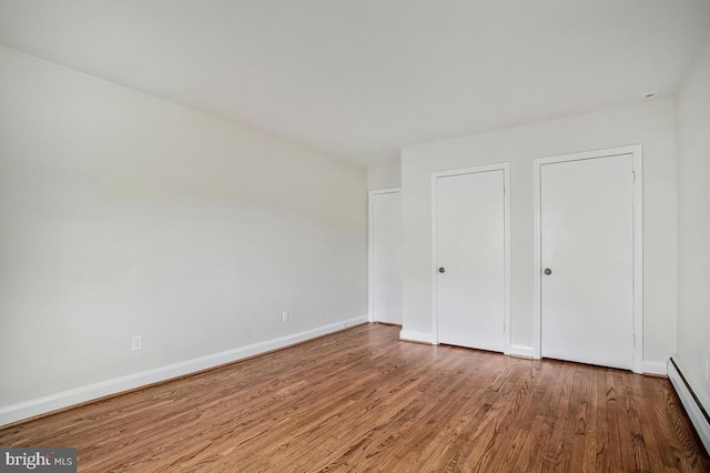 8205 Robin Hood Ct, Towson, MD 21204 - unfurnished bedroom featuring a baseboard heating unit, wood finished floors, and baseboards