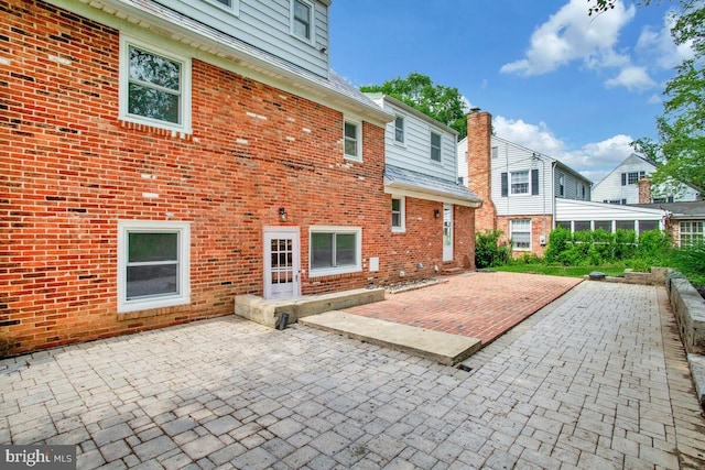 8205 Robin Hood Ct, Towson, MD 21204 - back of house with brick siding, a patio, and a chimney