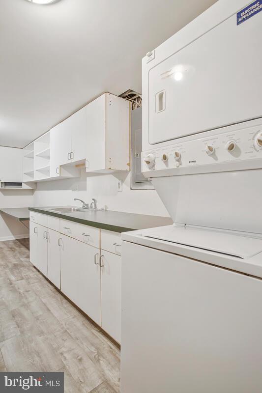 8205 Robin Hood Ct, Towson, MD 21204 - laundry room featuring estacked washer and dryer, cabinet space, and light wood-style flooring