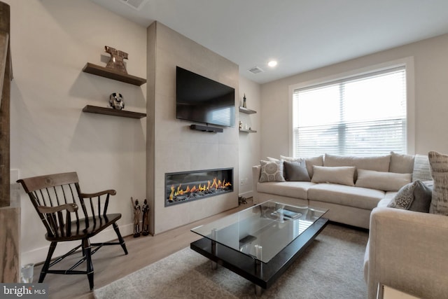 living area with wood finished floors, a fireplace, visible vents, and recessed lighting