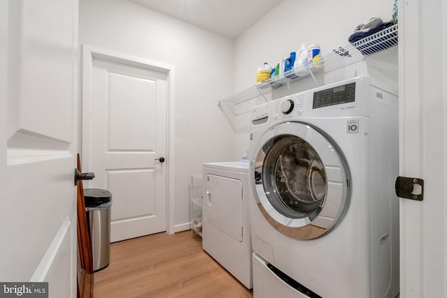 laundry area featuring light wood-type flooring, laundry area, and washing machine and clothes dryer