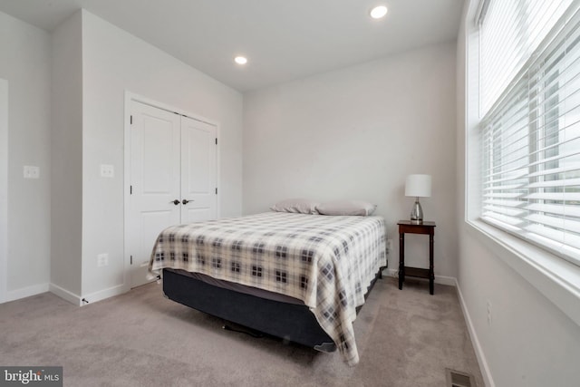 bedroom featuring light carpet, visible vents, and multiple windows