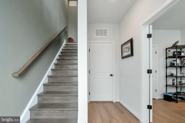 stairway featuring wood finished floors, baseboards, and visible vents