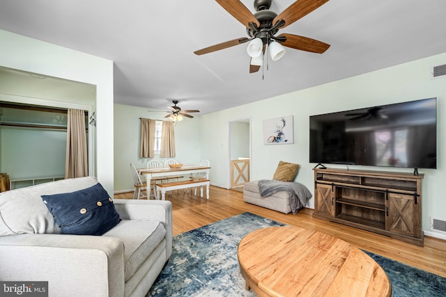 living room featuring visible vents, a ceiling fan, and wood finished floors