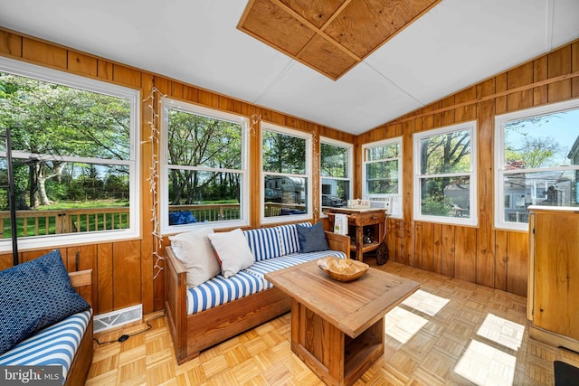 sunroom / solarium with an outdoor living space, vaulted ceiling, wood walls, and visible vents
