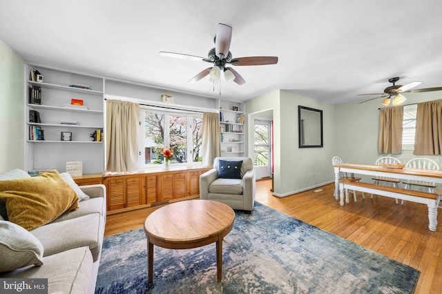 living area with a ceiling fan, baseboards, and wood finished floors