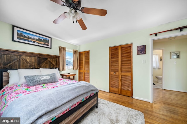 bedroom featuring baseboards, a ceiling fan, multiple closets, and wood finished floors