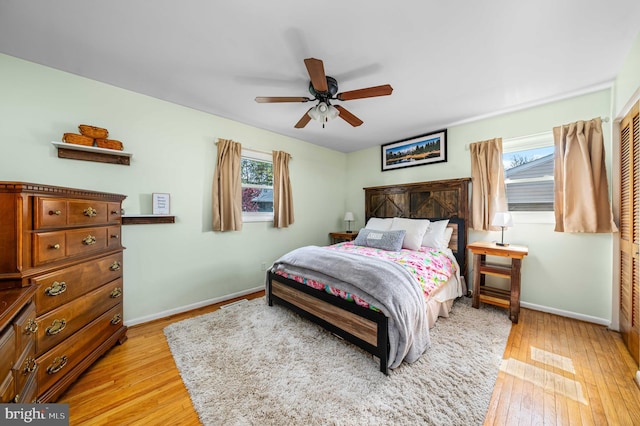 bedroom featuring baseboards, light wood-style floors, ceiling fan, and multiple windows