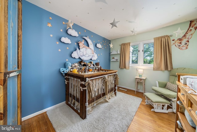 bedroom featuring baseboards, wallpapered walls, and wood finished floors