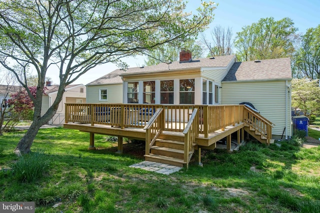 back of property featuring a shingled roof, a wooden deck, stairway, a chimney, and a lawn