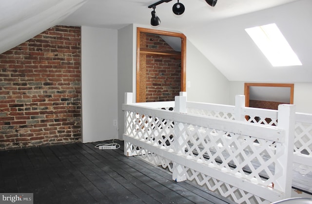 additional living space featuring vaulted ceiling, wood-type flooring, and brick wall