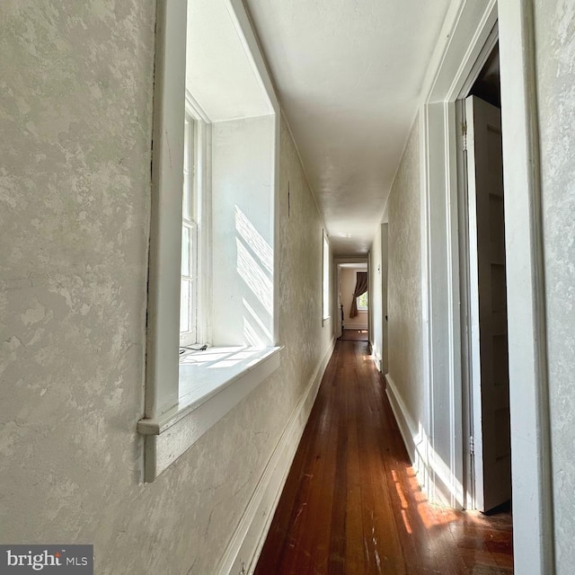 hall with a textured wall and hardwood / wood-style flooring