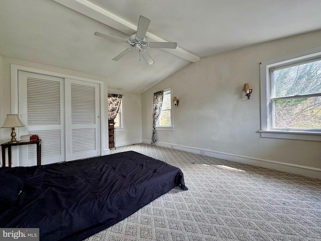 carpeted bedroom featuring a closet, ceiling fan, baseboards, and vaulted ceiling with beams