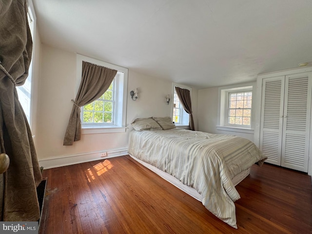 bedroom with a closet, baseboards, and hardwood / wood-style flooring