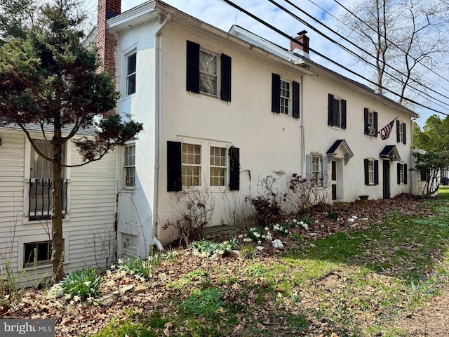 view of property exterior with stucco siding and a chimney