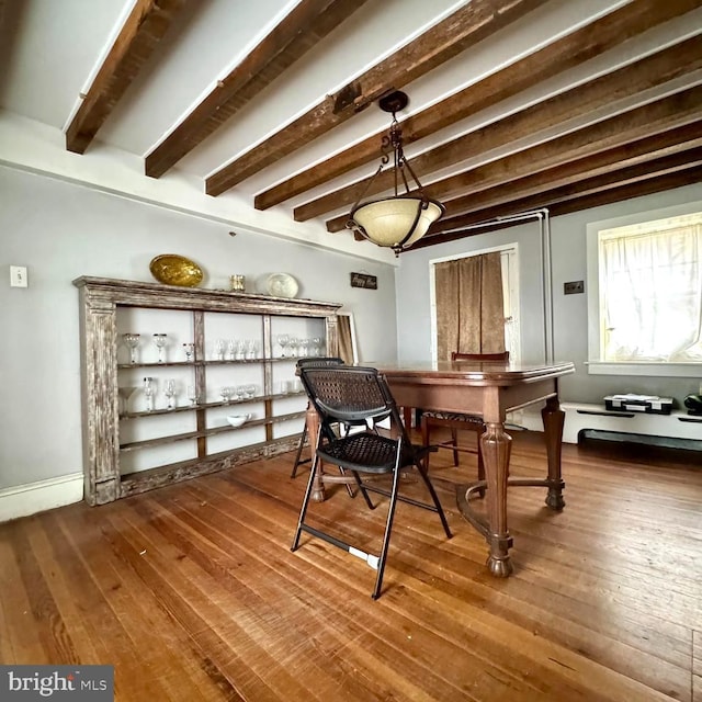 dining space featuring wood-type flooring and beamed ceiling