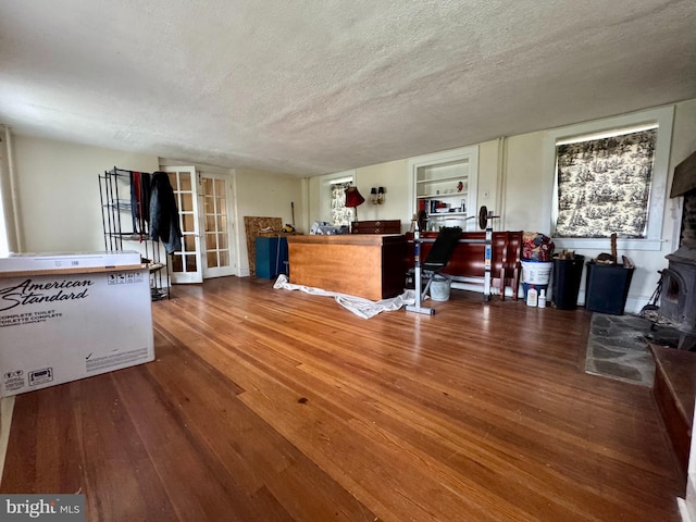 interior space with a wood stove, a textured ceiling, and wood finished floors