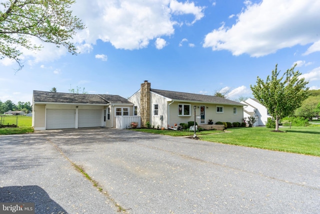 view of front facade featuring asphalt driveway, an attached garage, and a chimney