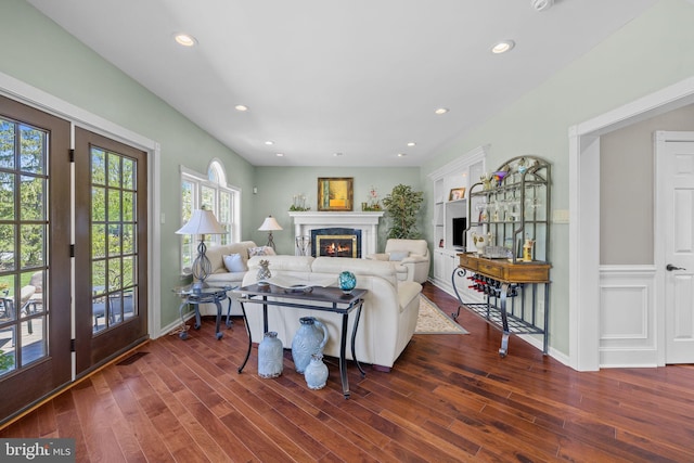 living area with recessed lighting, a warm lit fireplace, visible vents, and wood finished floors