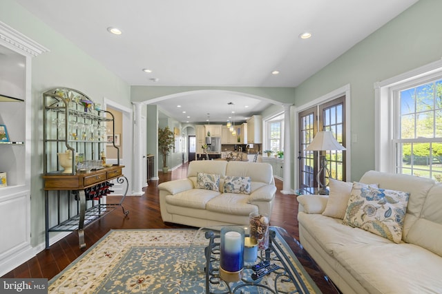 living area with recessed lighting, arched walkways, decorative columns, and dark wood finished floors