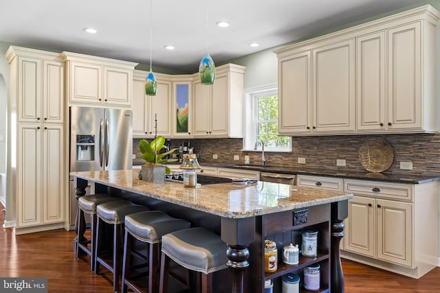 kitchen featuring a breakfast bar, dark wood-style floors, a center island, dark stone counters, and backsplash