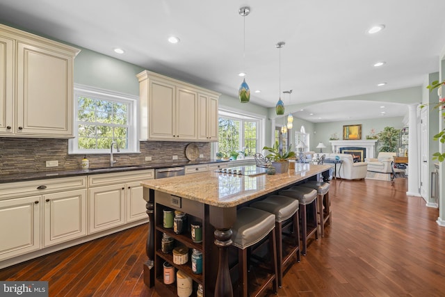 kitchen featuring a sink, dark stone counters, cream cabinets, and a kitchen island