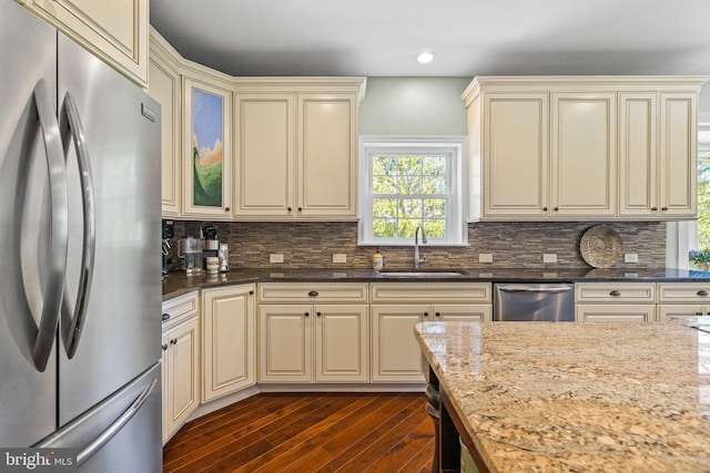 kitchen featuring dark wood-style flooring, a sink, appliances with stainless steel finishes, and cream cabinetry