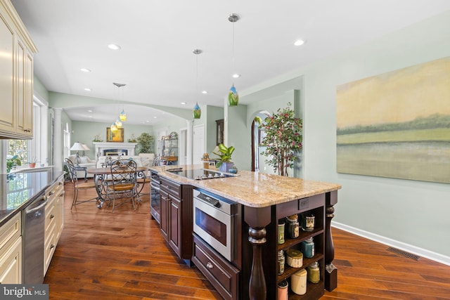 kitchen with ornate columns, dark wood-type flooring, appliances with stainless steel finishes, and arched walkways