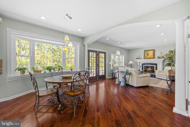 dining room with decorative columns, french doors, arched walkways, dark wood finished floors, and a premium fireplace
