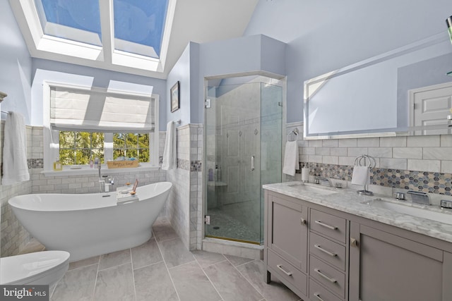 bathroom with double vanity, a freestanding tub, tile walls, a sink, and a stall shower
