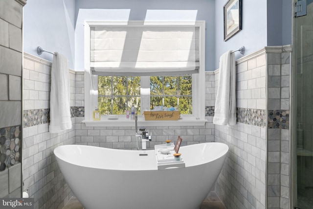 bathroom with a freestanding bath, tile walls, a wainscoted wall, and a stall shower