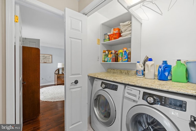 washroom featuring laundry area, washing machine and dryer, baseboards, ornamental molding, and dark wood-type flooring
