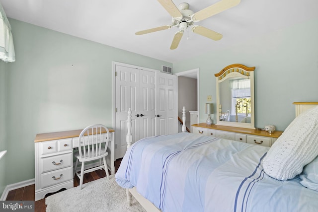 bedroom featuring visible vents, a closet, wood finished floors, baseboards, and a ceiling fan