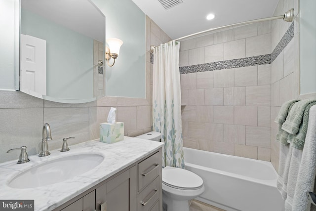 full bathroom featuring vanity, toilet, shower / bath combo with shower curtain, tile walls, and visible vents