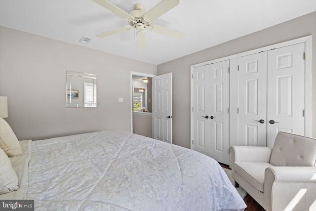 bedroom featuring multiple closets, ceiling fan, wood finished floors, and visible vents