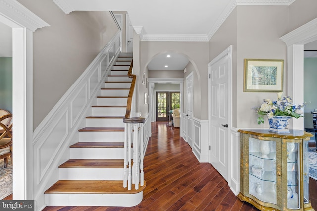staircase featuring arched walkways, ornamental molding, and wood finished floors