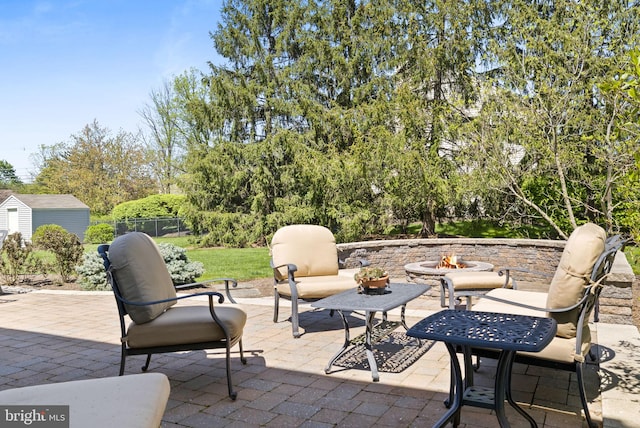 view of patio / terrace with a storage shed, fence, an outbuilding, and a fire pit