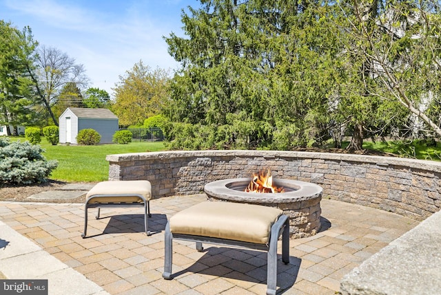 view of patio / terrace featuring an outbuilding, a fire pit, and a storage unit
