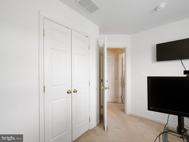 bedroom with a closet, visible vents, baseboards, and light carpet