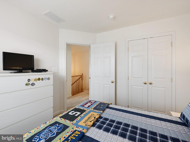 carpeted bedroom with a closet, visible vents, and baseboards