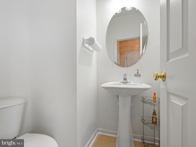 bathroom with toilet, baseboards, and a sink