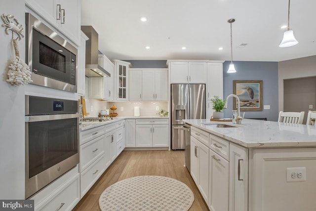 170 Harrier Way Unit 32, Chester, MD 21619 - kitchen featuring wall chimney range hood, a sink, an island with sink, stainless steel appliances, and white cabinetry