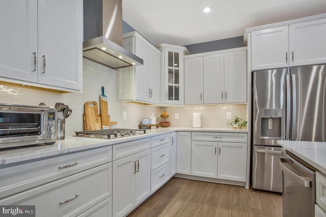 170 Harrier Way Unit 32, Chester, MD 21619 - kitchen featuring light wood-type flooring, wall chimney exhaust hood, tasteful backsplash, appliances with stainless steel finishes, and white cabinetry