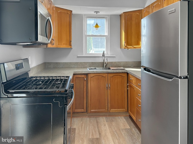 kitchen with appliances with stainless steel finishes, light wood-style flooring, brown cabinets, and pendant lighting